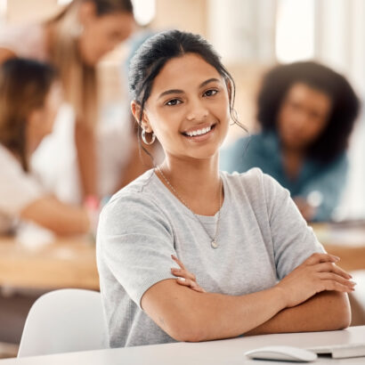 Computer, learning and education with a woman student sitting at a desk in the classroom for study .